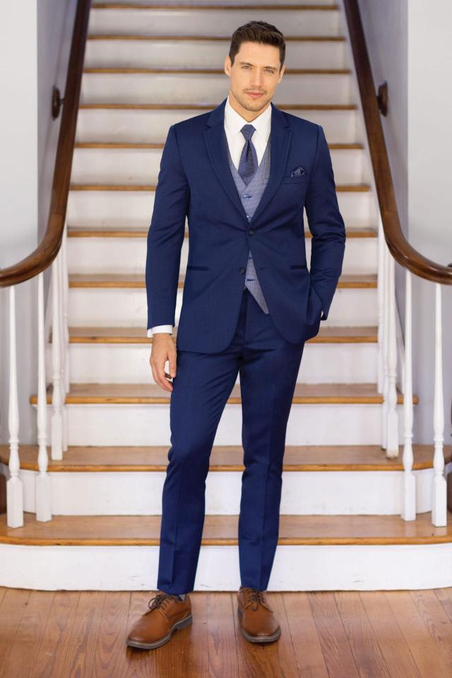 man in Michael Kors Blue Performance suit and Foundations Blue vest and tie standing in front of a staircase